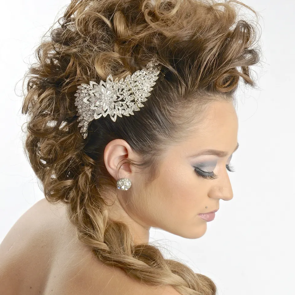 Glam updo with a sculpted curly crown, side braid and jeweled hairpiece